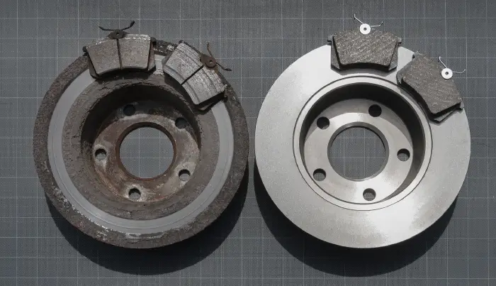 Worn brake pads and damaged brake rotor comparison during brake repair